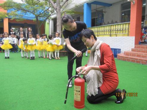 小何现场教幼儿园老师怎样正确操作灭火器。